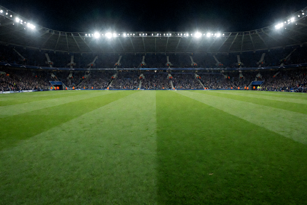 足球场全景夜景灯光下的绿茵草坪，展现职业足球赛事场馆氛围