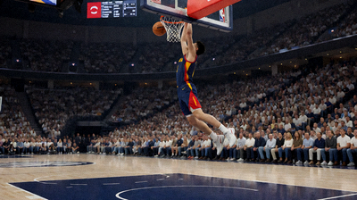 NBA篮球比赛现场，球员在空中扣篮，观众席人头攒动，球场木地板反光